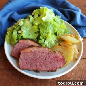 Dinner plate filled with slices of smoked corned beef brisket, fried potatoes, and wilted lettuce.