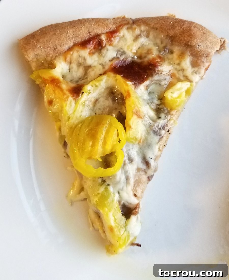 slice of Italian beef pizza with peppers and golden cheese ready to eat.