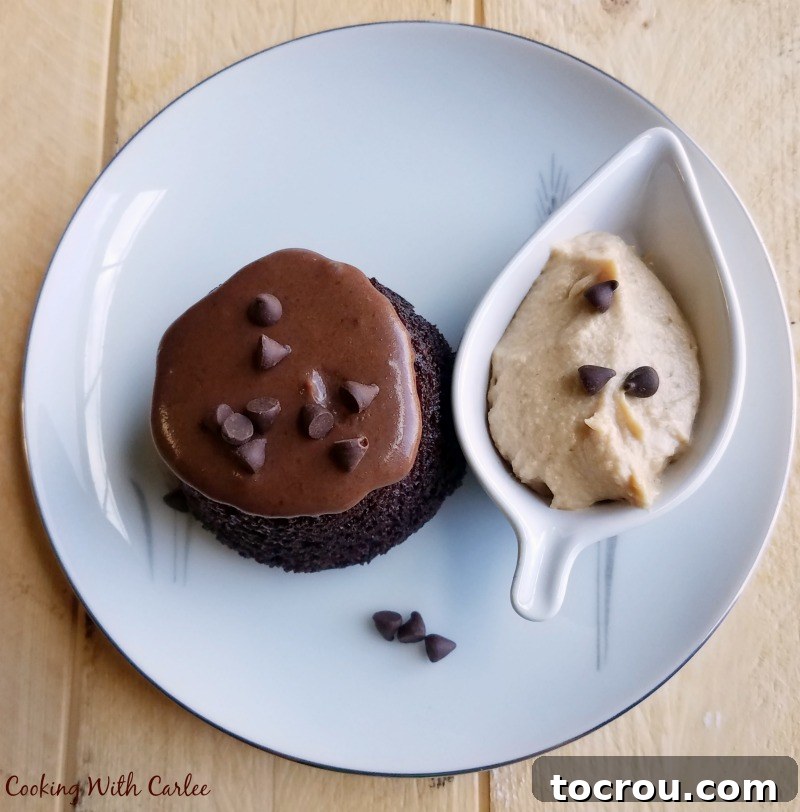 An upside-down chocolate cupcake, mimicking a mini bundt cake, with chocolate glaze, mini chocolate chips, and a small leaf-shaped bowl of peanut butter whipped cream.