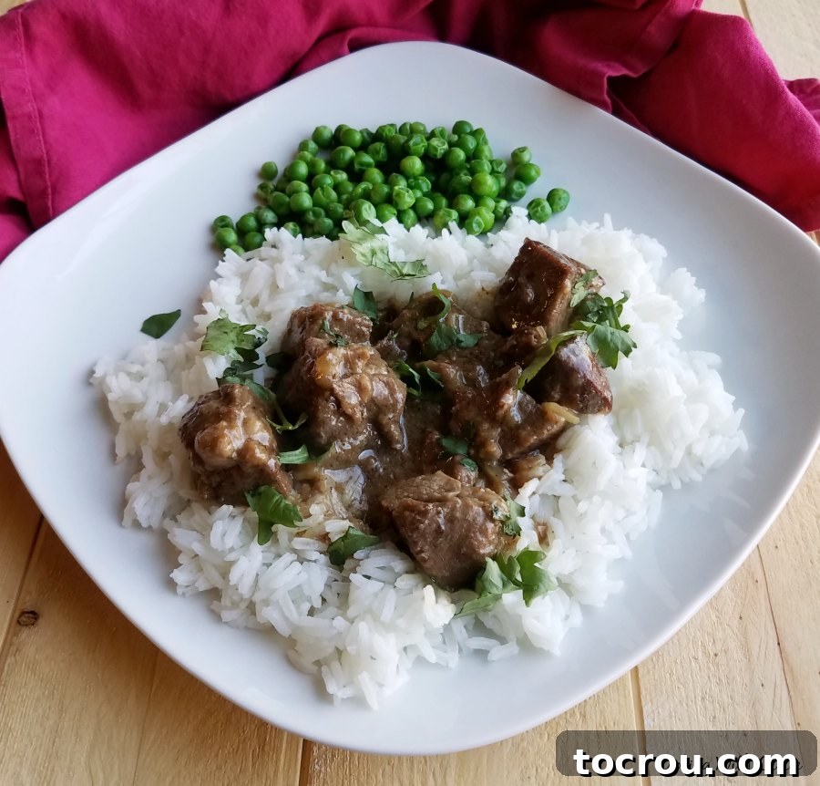 A beautifully plated serving of Maw-Maw's lamb curry, accompanied by bright green peas, showcasing a complete and comforting dinner.
