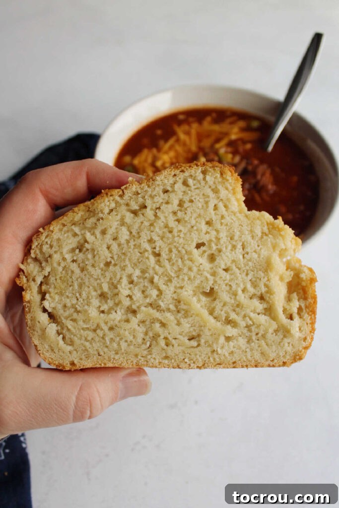 Doris Tangy Cider Loaf 4 Hand holding slice of beer bread in front of pulled pork chili.