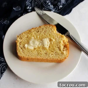 Small plate with slice of beer bread topped with melty butter, ready to eat.