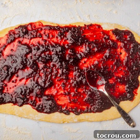 Spreading blackberry compote over a rectangle of dough.