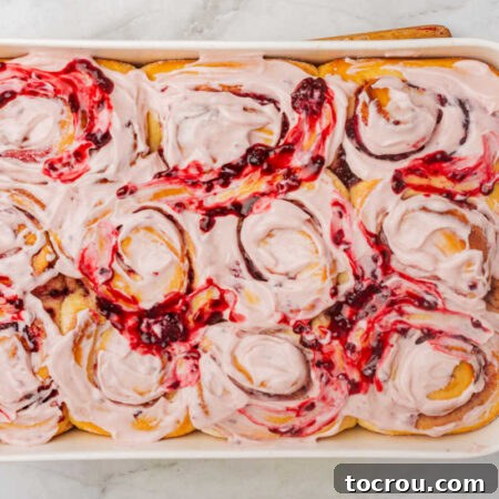 Pan of frosted blackberry sweet rolls with a swirl of blackberry compote on top.