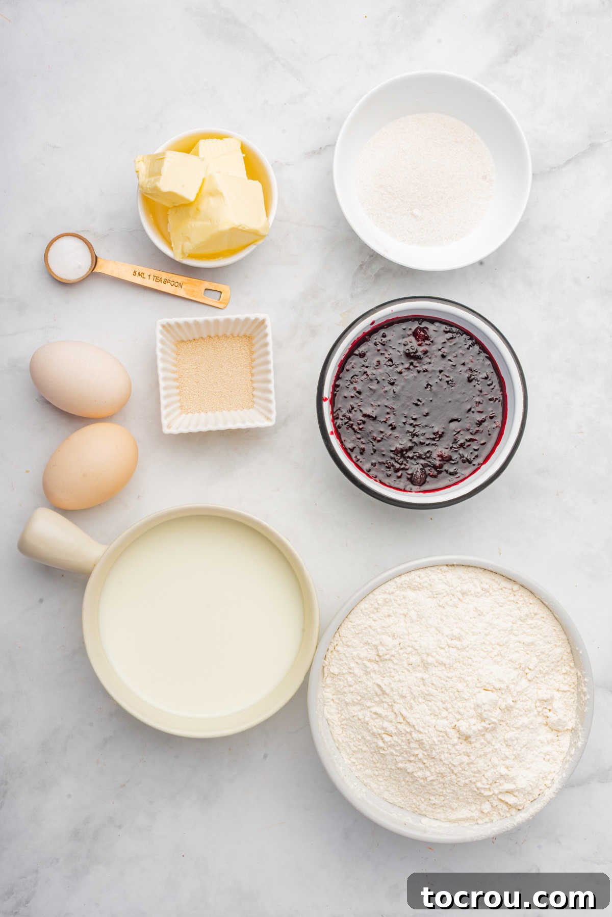 Ingredients including flour, butter, sugar, milk, eggs, yeast, and blackberry compote, ready to be made into blackberry sweet rolls.