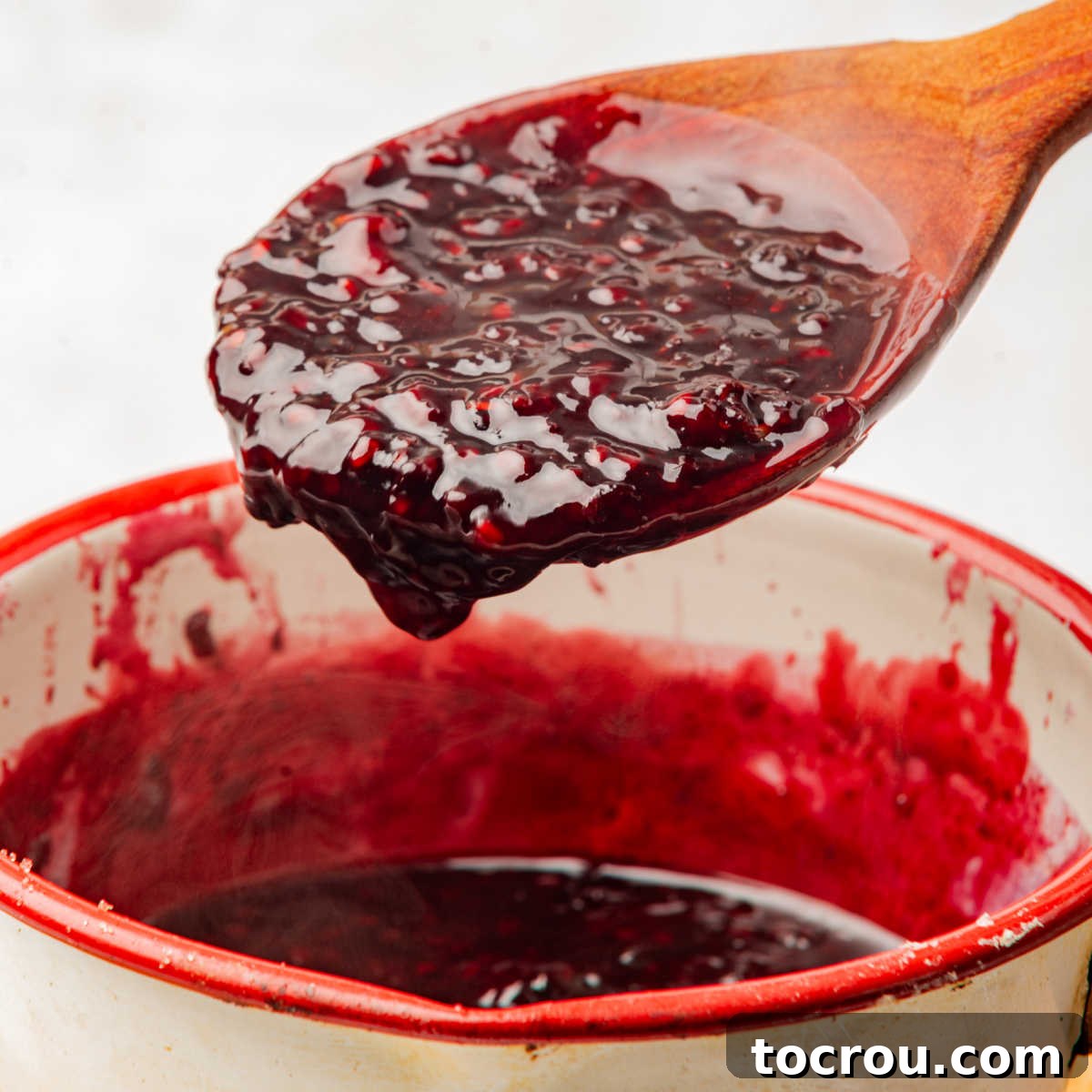 Spoon filled with finished blackberry compote, showcasing its thick, jam-like consistency and the breakdown of berries.