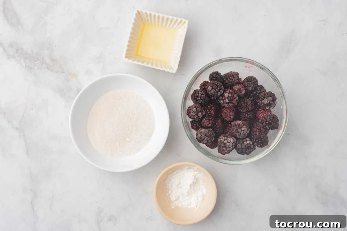 A vibrant bowl of fresh blackberries, granulated sugar, and a lemon, showcasing the simple, wholesome ingredients for the compote.