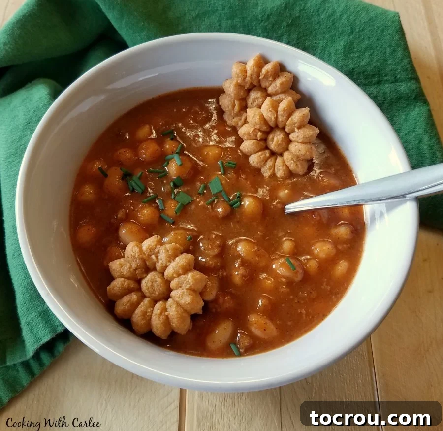 Warm and comforting Apple Ale Pumpkin Chili topped with crackers. bowl of pumpkin chili with crackers on top.