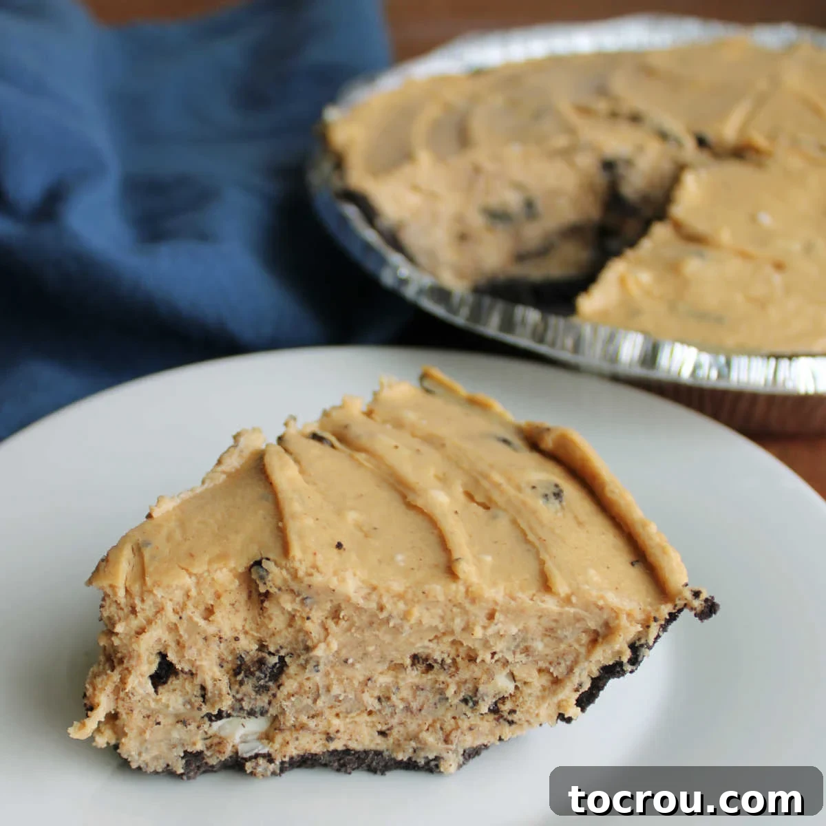 Slice of rock bottom pie with no bake peanut butter pie filling dotted with pieces of Oreos in chocolate crust, ready to eat.