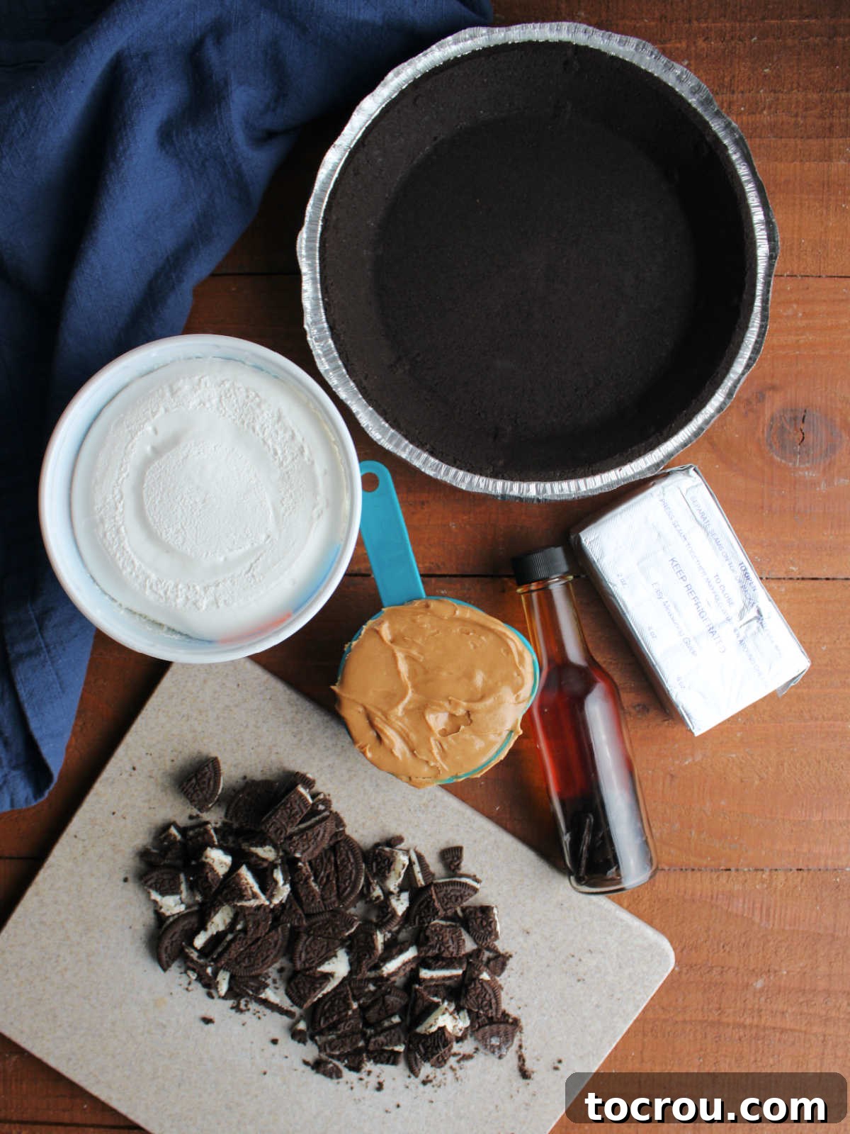 Ingredients including chocolate cookie crumb crust, peanut butter, cream cheese, vanilla, Cool Whip and Oreos ready to be made into rock bottom pie. 