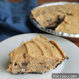 Slice of rock bottom pie with no bake peanut butter pie filling dotted with pieces of Oreos in chocolate crust, ready to eat.