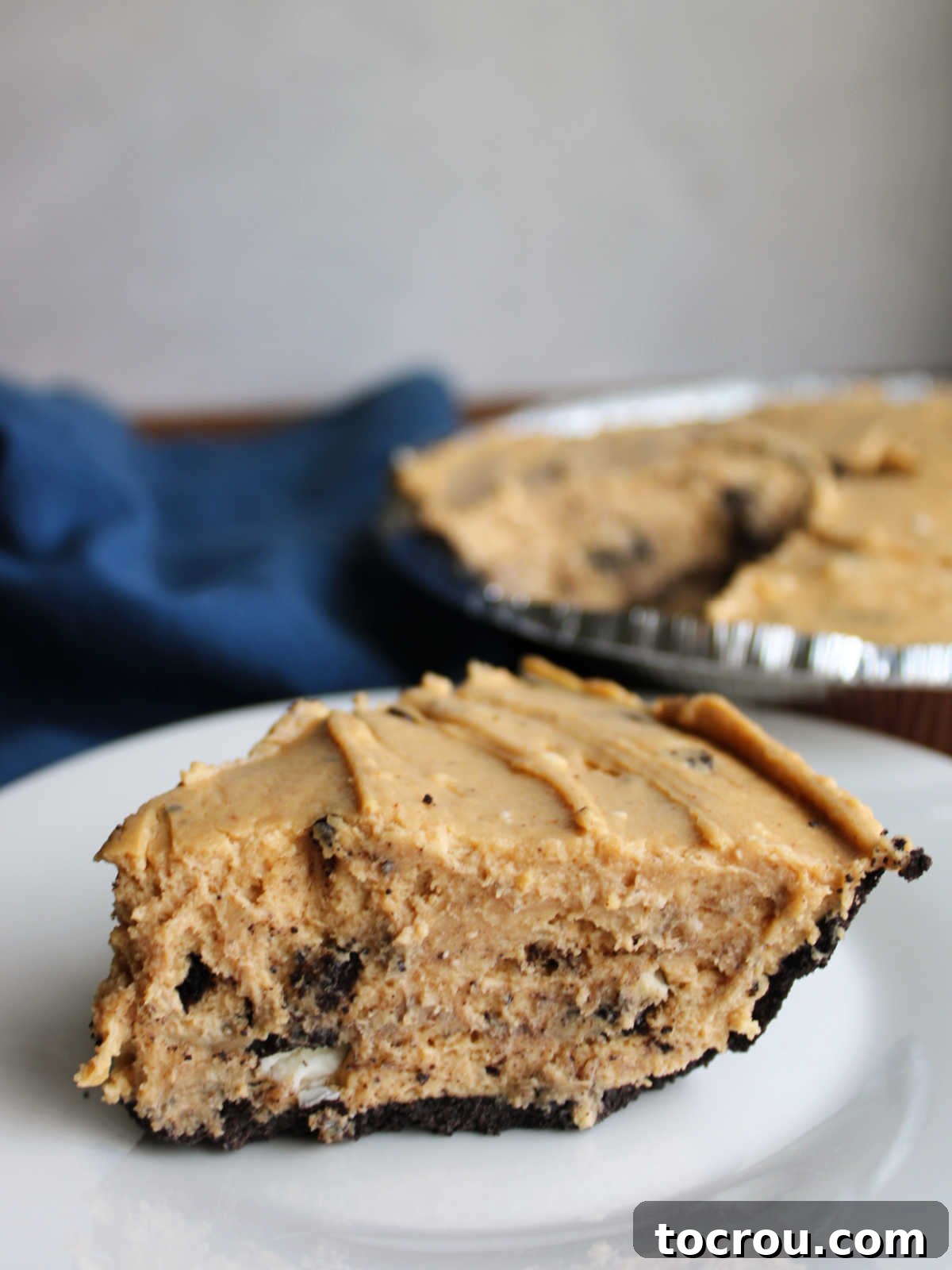 Slice of rock bottom pie with no bake peanut butter pie filling dotted with pieces of Oreos in chocolate crust, ready to eat.