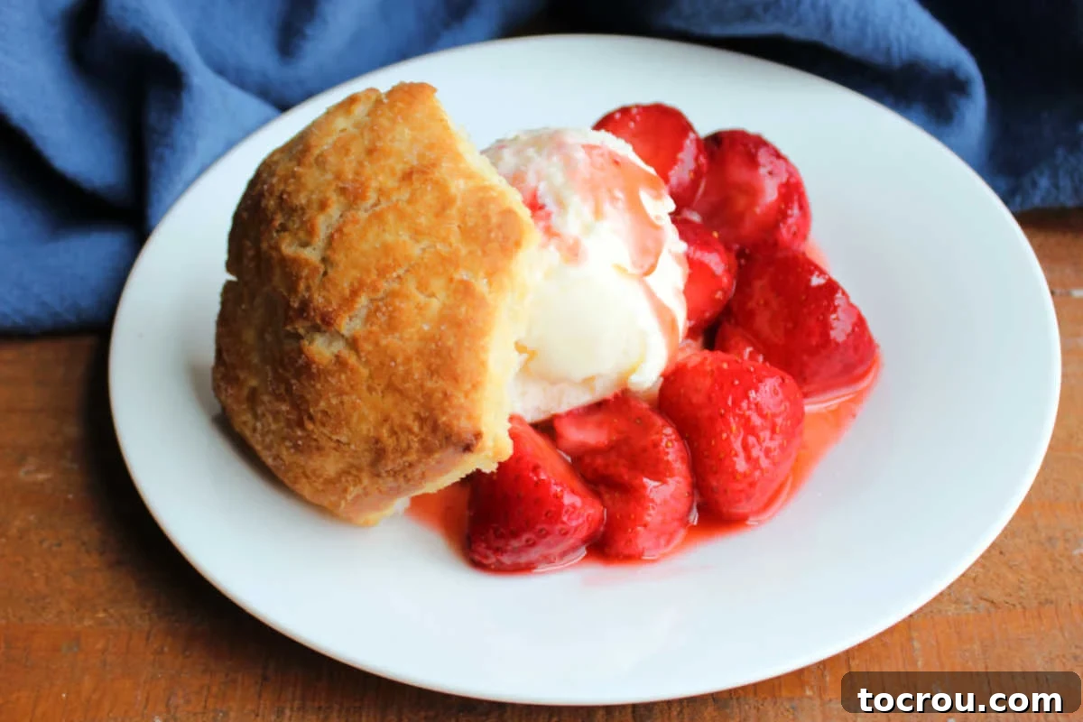 Perfectly Sweet Shortcake Biscuits 2 Small plate with a biscuit style strawberry shortcake with golden brown biscuit, vanilla ice cream, and strawberry sauce.