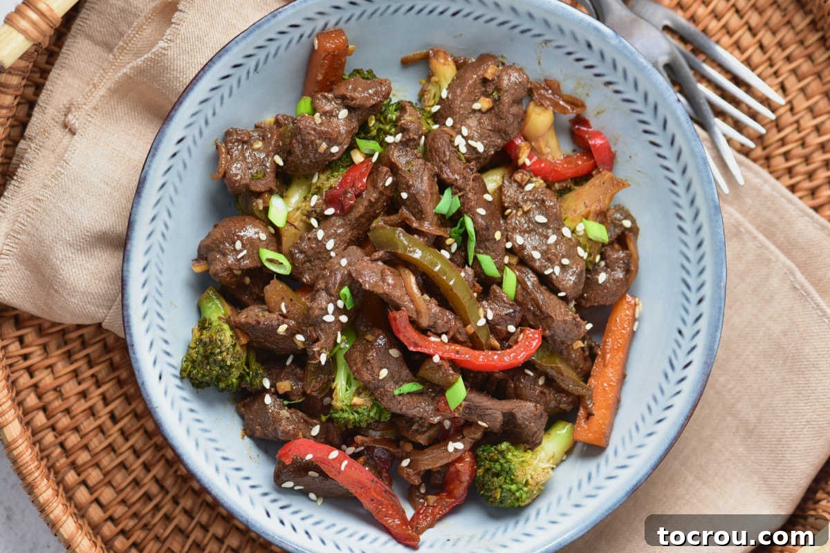 Plate of stir fry with pieces of venison, peppers, carrots, onion and broccoli topped with sesame seeds. 