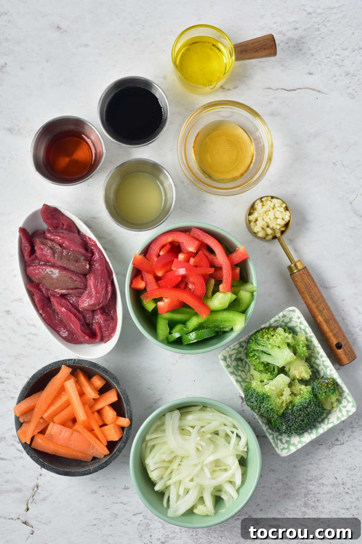 Stir fry ingredients including venison, bell pepper, onion, carrots, oil, soy sauce, honey, lemon juice, and garlic. 