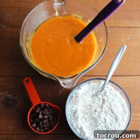 Harvest Pumpkin Bundt Cake with Cream Cheese Core 11 A bowl of vibrant orange wet ingredients, including pumpkin, next to a bowl of dry, mixed ingredients. A measuring cup filled with chocolate chips sits ready for incorporation into the cake batter.