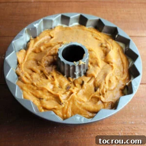 Harvest Pumpkin Bundt Cake with Cream Cheese Core 15 The remaining pumpkin cake batter perfectly smoothed over the cream cheese filling in the Bundt cake pan, creating a seamless top layer, ready to be baked.