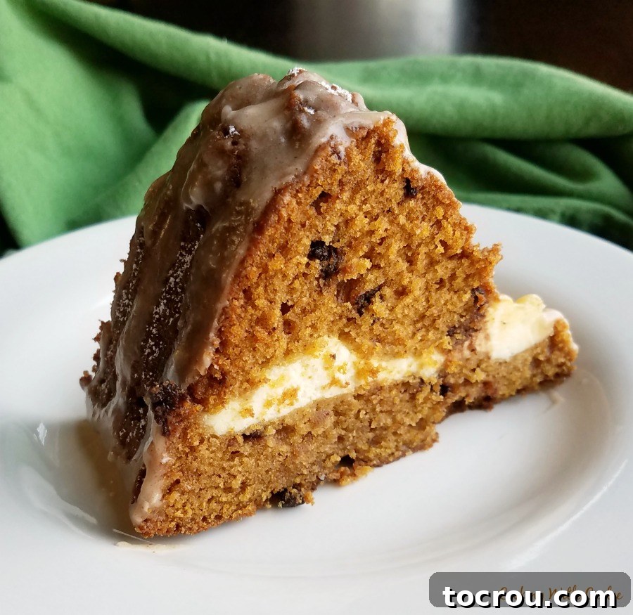 Harvest Pumpkin Bundt Cake with Cream Cheese Core 6 A close-up view of a slice of cheesecake-stuffed pumpkin Bundt cake, showcasing the luscious cream cheese filling and a glistening apple cider glaze.