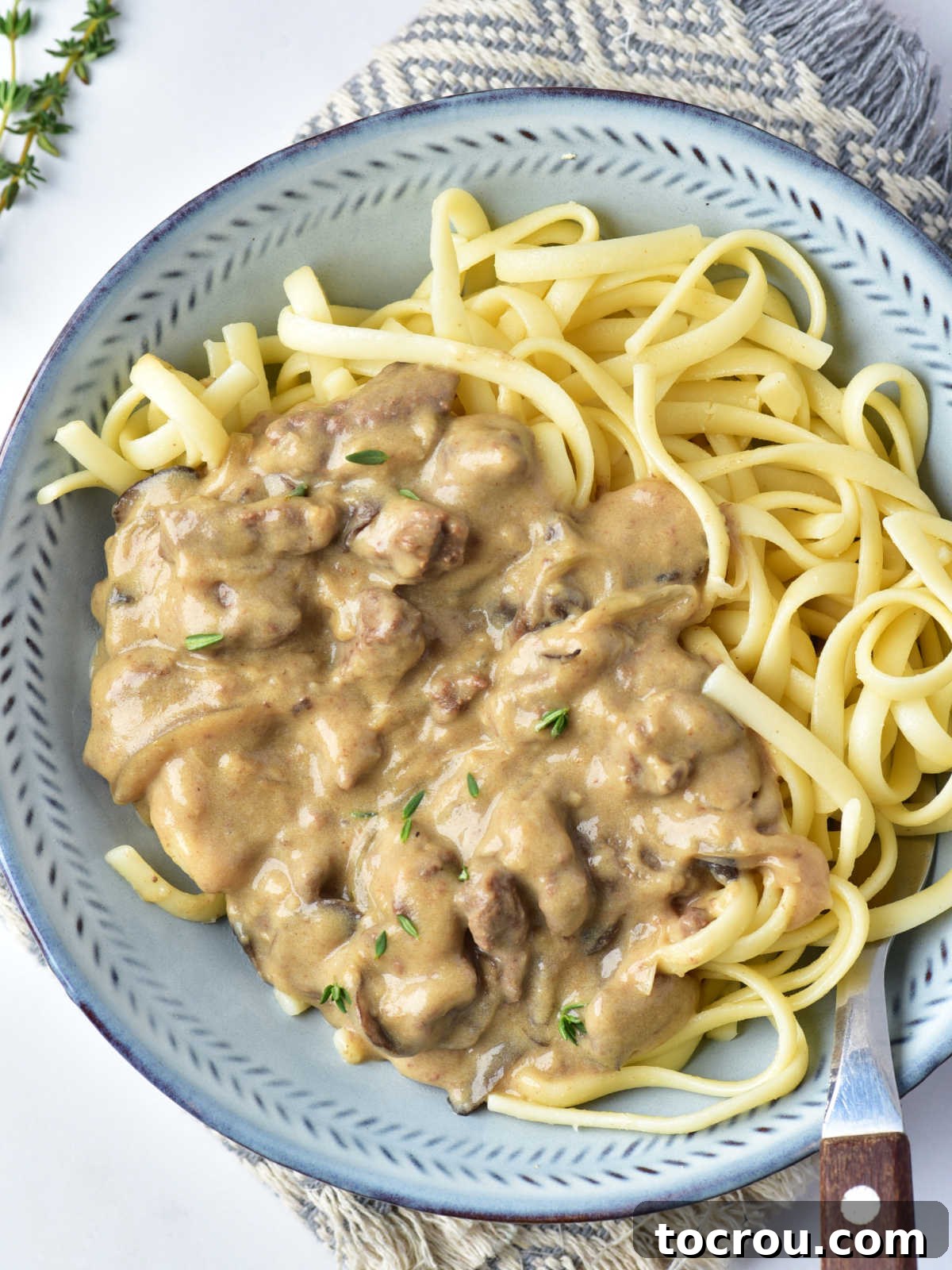 Rustic Venison Stroganoff 5 Creamy venison stroganoff served over pasta with fork, ready to eat.