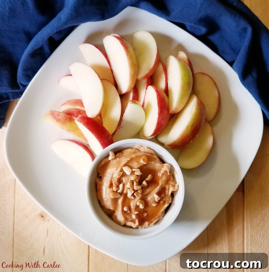 Creamy Peanut Butter Yogurt Dip: A Healthy Treat for Apples and More! looking down at a plate of sliced apples and a ramekin of peanut butter yogurt fruit dip.