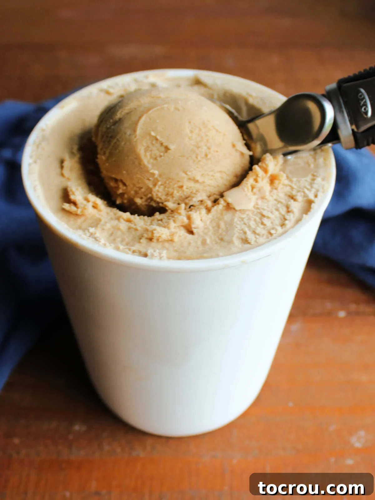 A scoop of luscious homemade coffee ice cream being gently removed from a sleek storage container, showcasing its creamy texture and inviting appeal.