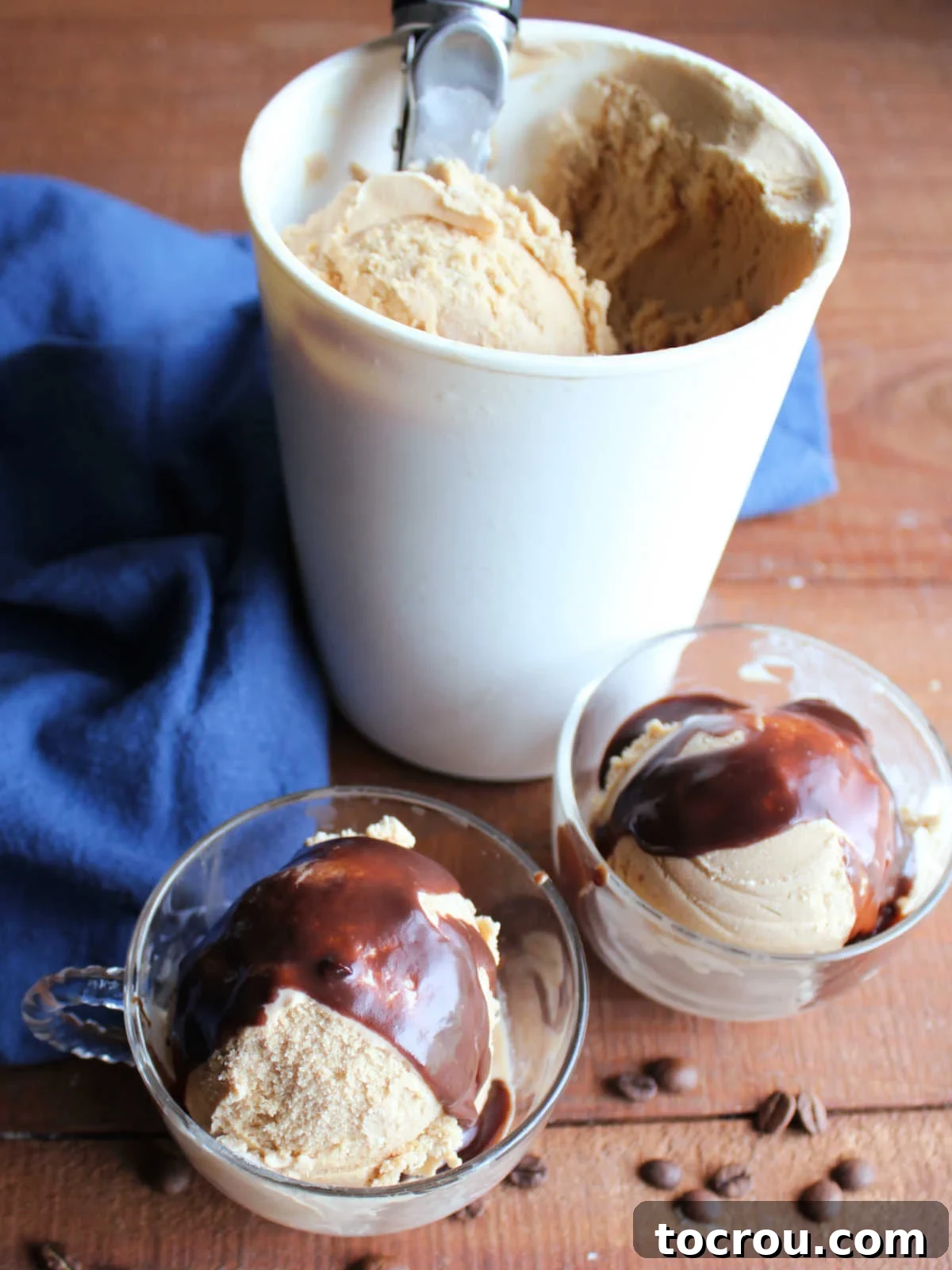 Mouth-watering hot fudge sauce lavishly drizzled over cups of creamy homemade coffee ice cream, highlighting its inviting and indulgent appeal.