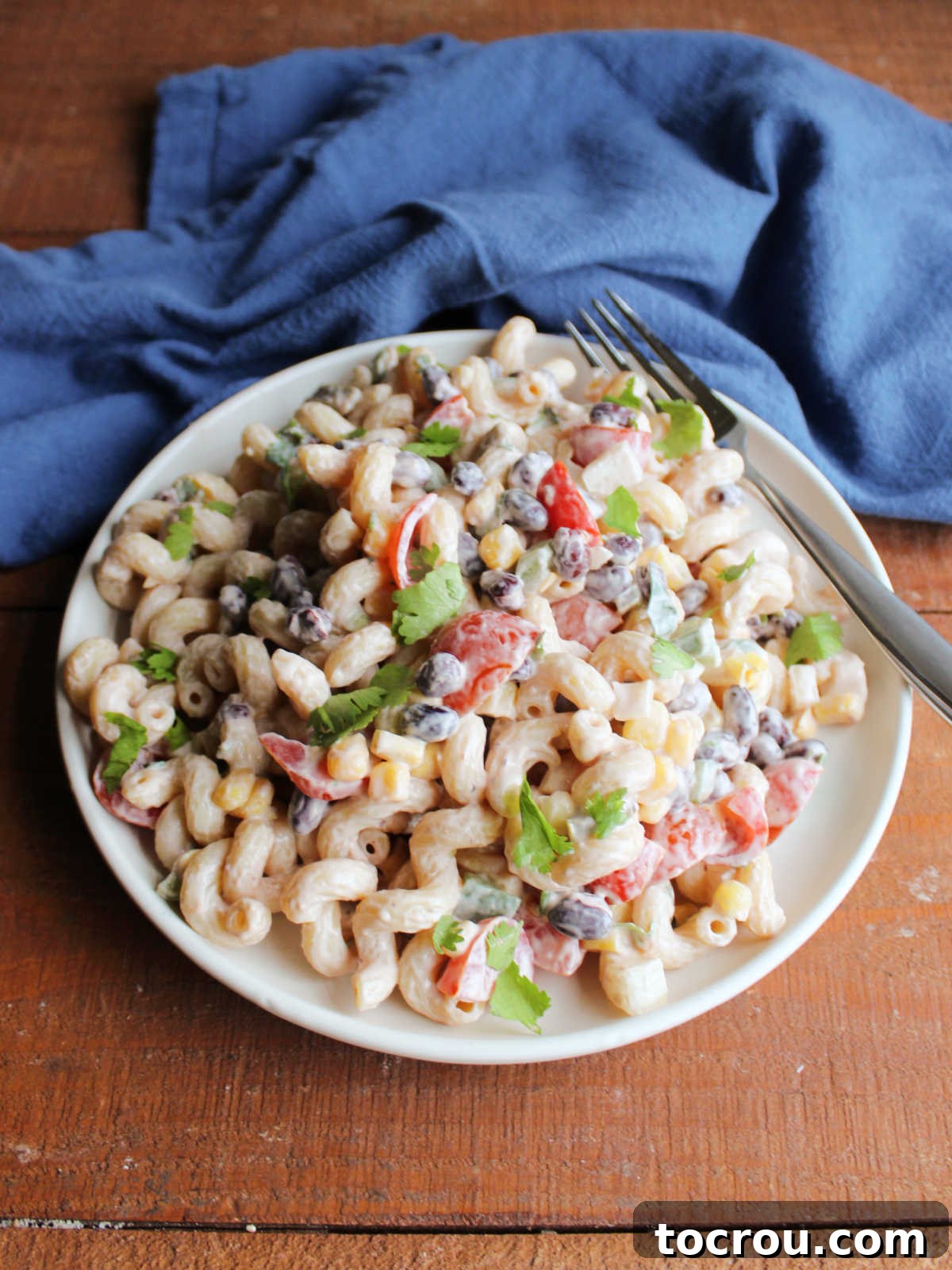 Lunch plate featuring a generous serving of creamy BBQ pasta salad, brimming with black beans, sweet corn, bell peppers, and juicy tomatoes.