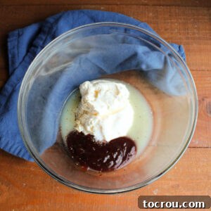 Mixing bowl with mayonnaise, BBQ sauce, lime juice, salt, and pepper inside, ready to be made into dressing for pasta salad.