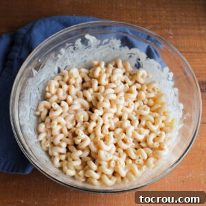 Mixing bowl of cooked pasta coated in creamy BBQ dressing.