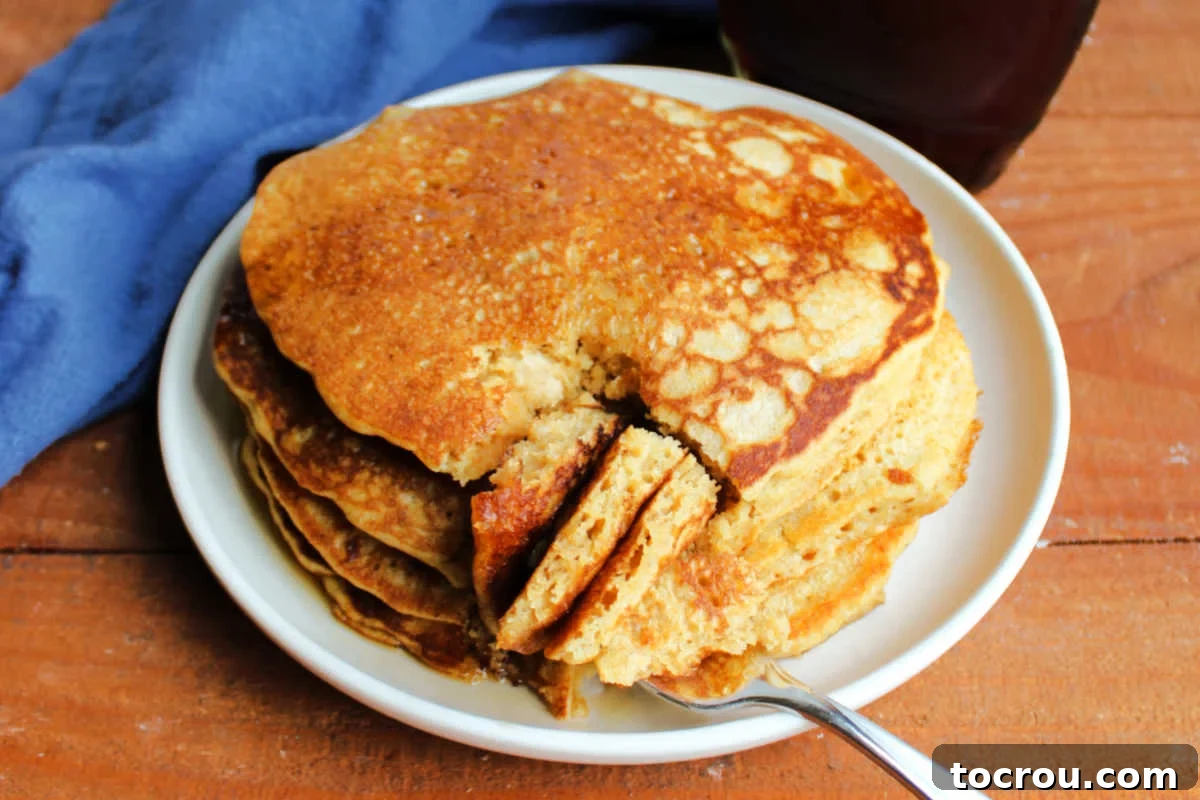 Plate of fluffy whole wheat sourdough pancakes with a bite of pancakes on fork. 
