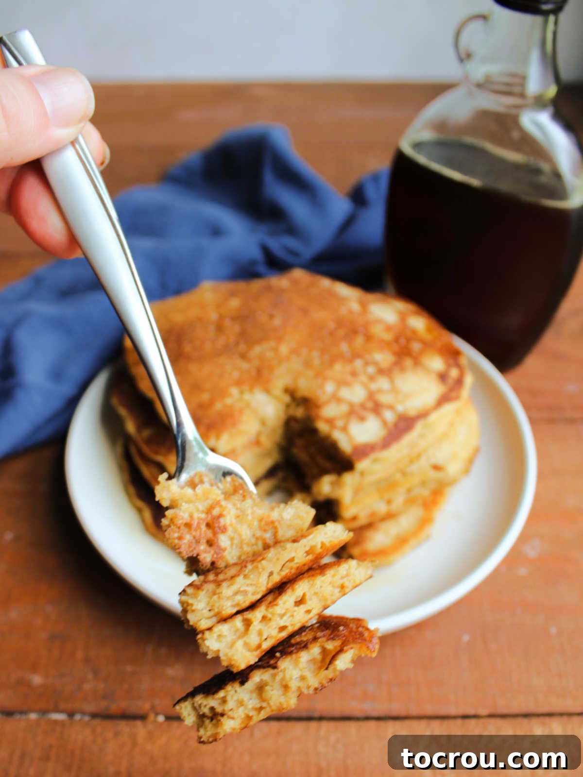 Big bite of sourdough pancakes on fork showing fluffy interior and golden brown exterior, ready to eat. 