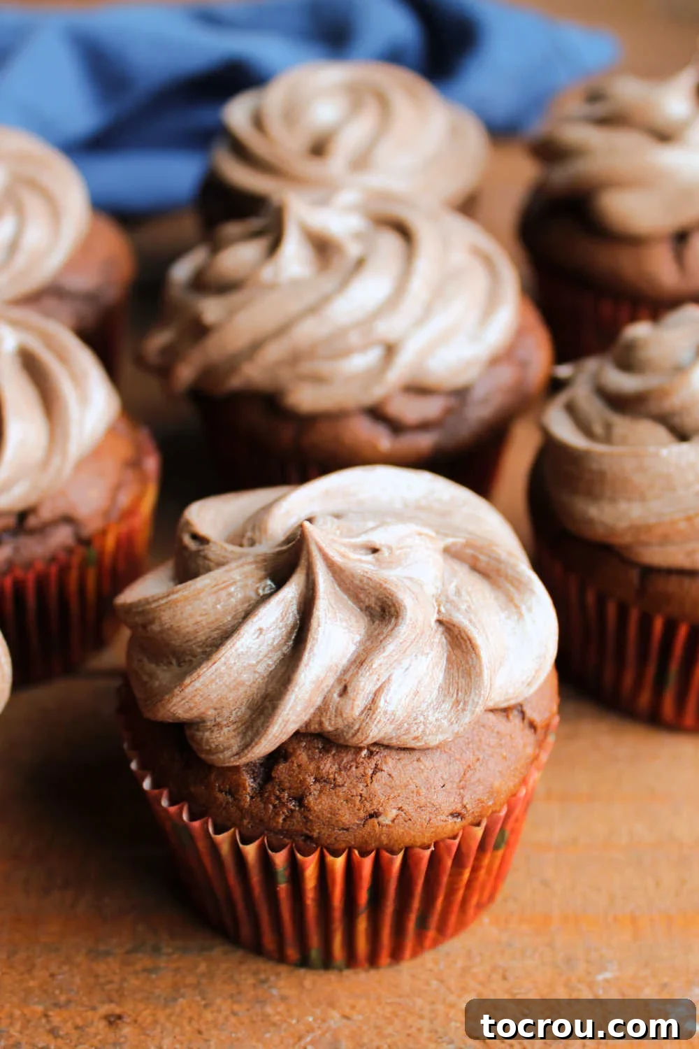 Two chocolate cupcakes elegantly topped with ruffled swirls of chocolate ermine frosting, ready to be devoured.