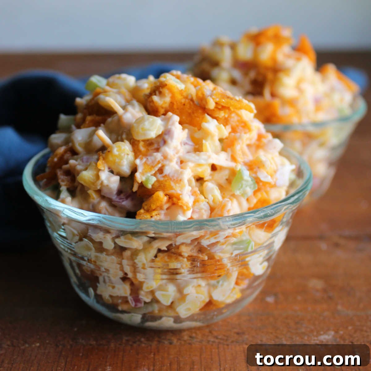 Zesty Frito Corn Crunch 2 Small glass bowls piled high with Frito corn salad, featuring creamy dressing, bits of red onion and green pepper, and crushed chili cheese Fritos, ready to eat.