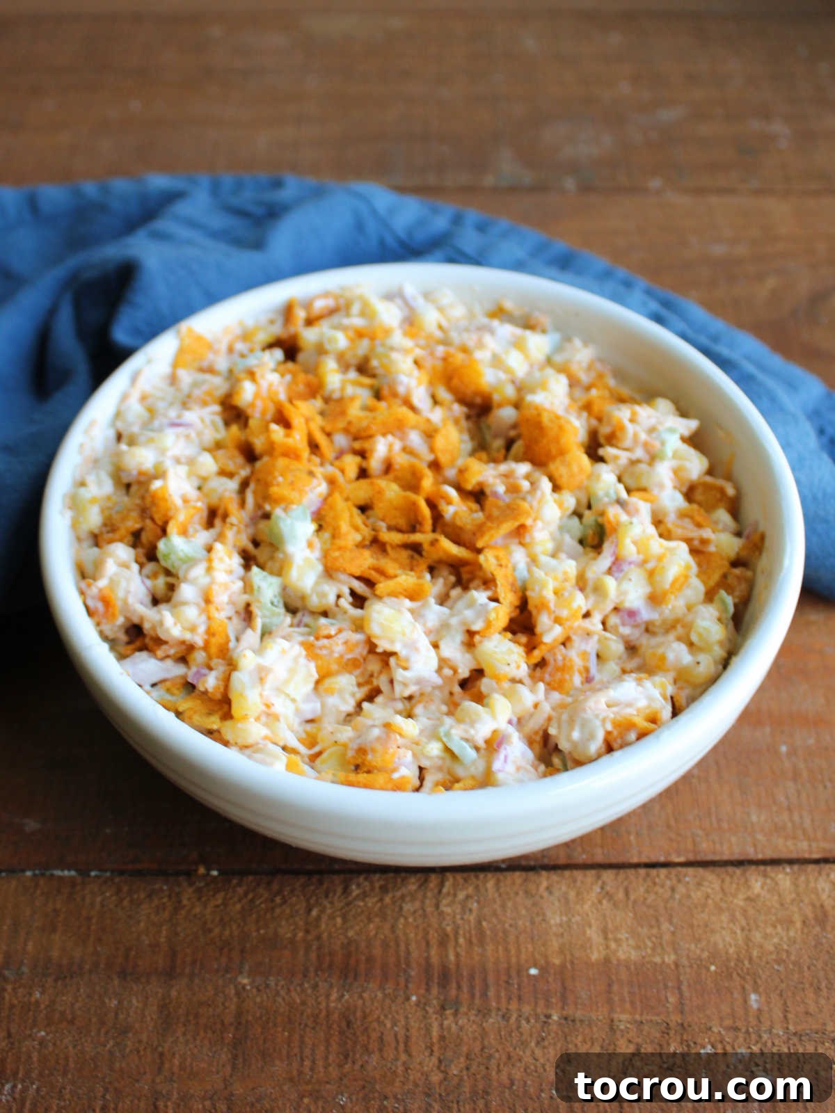 Zesty Frito Corn Crunch 4 A serving bowl generously filled with vibrant chili cheese Frito corn salad, garnished and ready to be shared and enjoyed.