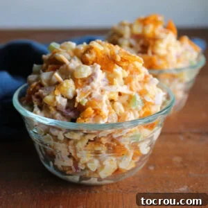 Small glass bowls piled high with corn salad with creamy dressing, bits of red onion and green pepper, and crushed up pieces of chili cheese Fritos, ready to eat.