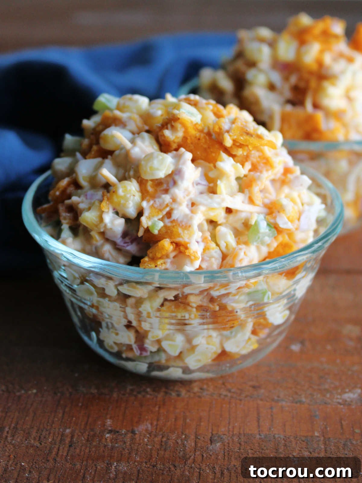 Small glass bowls piled high with Frito corn salad with creamy dressing, bits of red onion and green pepper, and crushed up pieces of chili cheese Fritos, ready to eat.