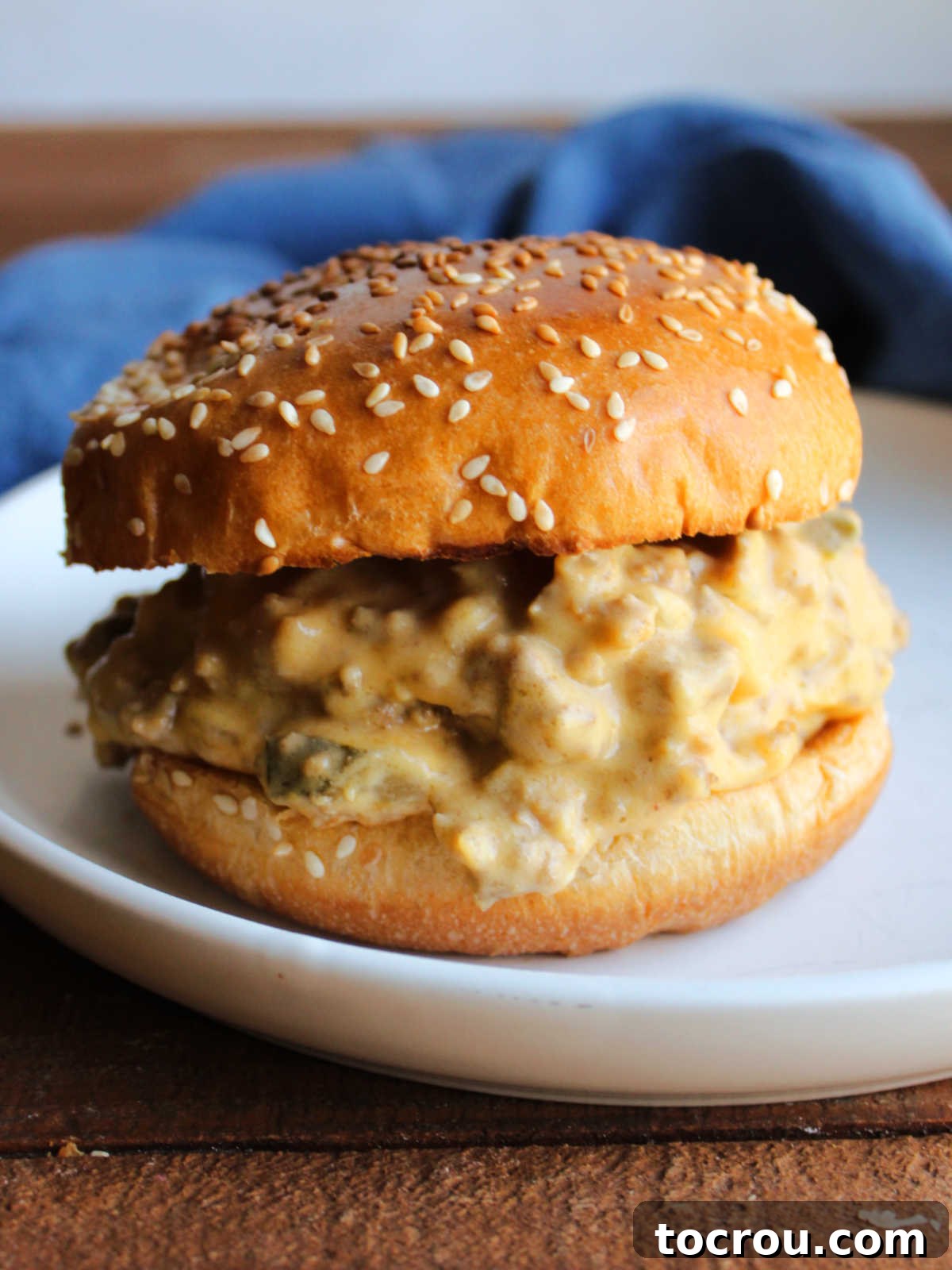 Close-up of a perfectly assembled crockpot cheeseburger sloppy joe sandwich on a toasted bun.