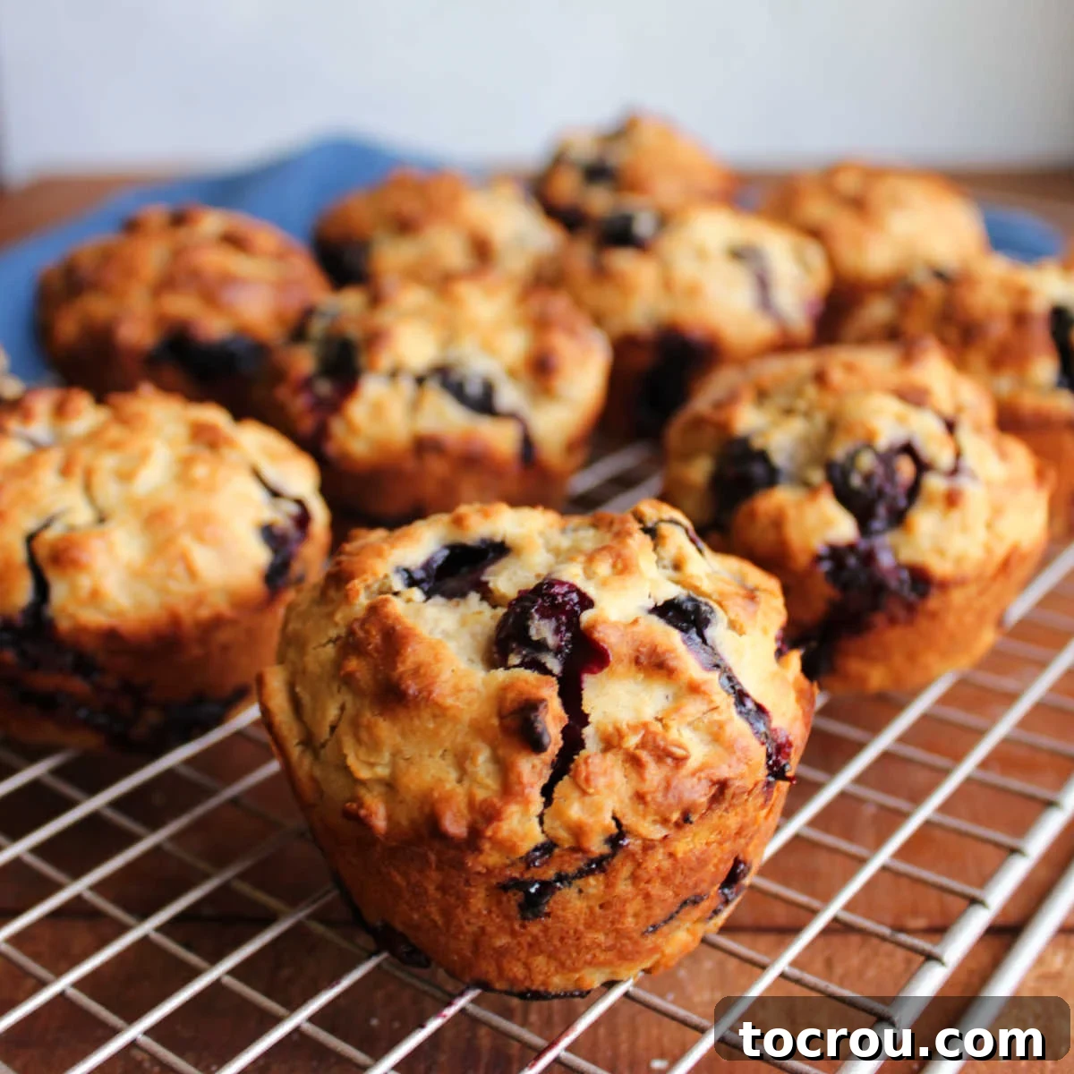 Freshly baked blueberry sourdough muffins on wire cooling rack showing golden brown exterior with pops of blueberries throughout.