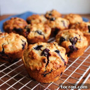 Freshly baked blueberry sourdough muffins on wire cooling rack showing golden brown exterior with pops of blueberries throughout.