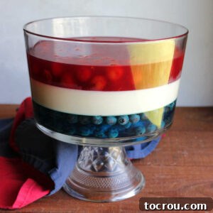 Patriotic Layered Jello 6 Glass trifle bowl filled with a layer of blue jello with blueberries topped with a white layer of jello with sweetened condensed milk, topped with a layer of cherry jello with cherry pie filling mixed in.