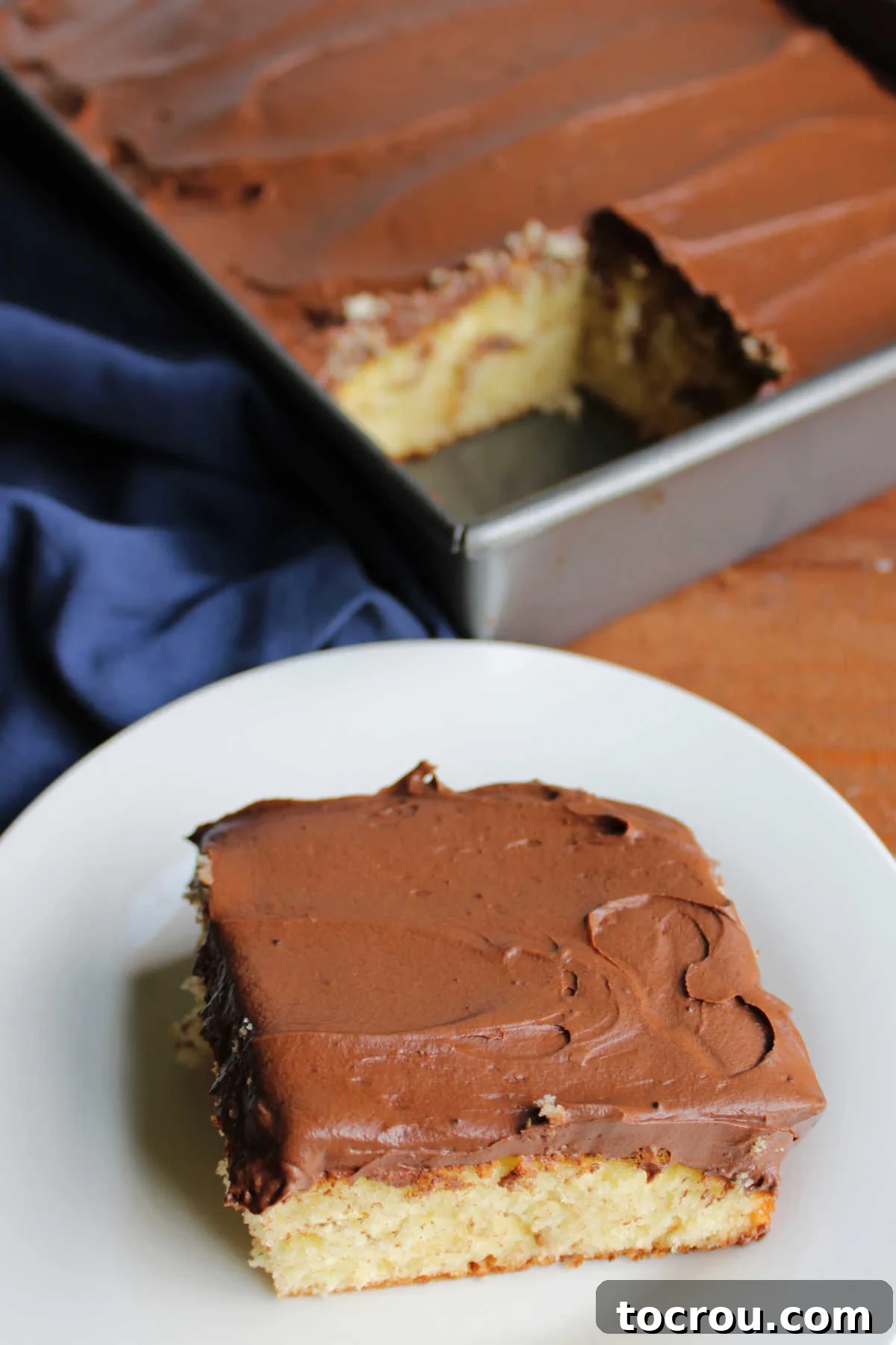 A delectable slice of cake, perfectly topped with smooth and creamy chocolate frosting, presented on a plate, irresistibly ready for enjoyment.