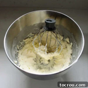 Mixer bowl with whipped butter inside, light and fluffy, ready for next step.