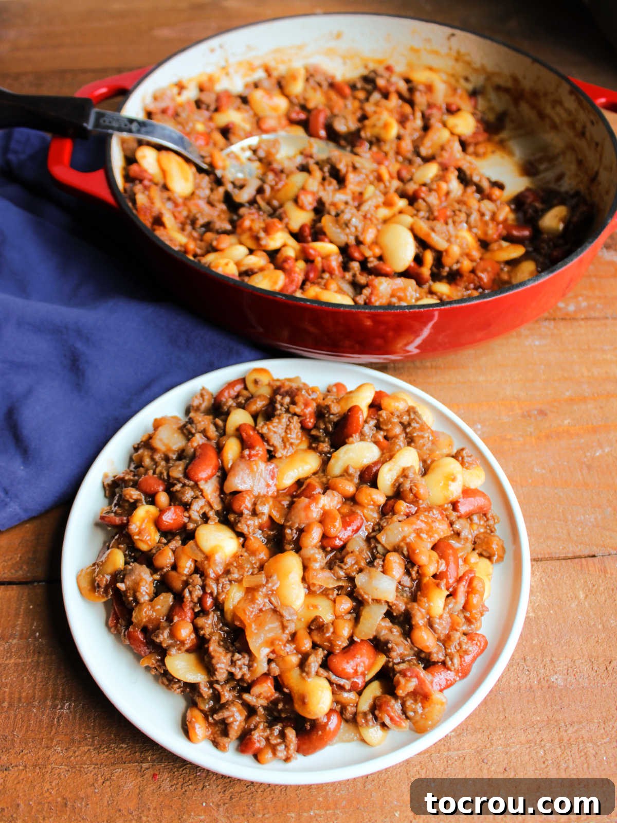 Plate of homemade calico beans in front of the pan they were cooked in. 