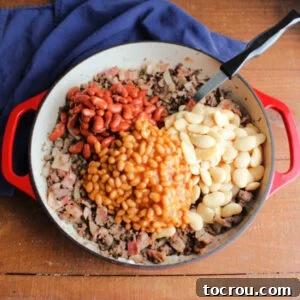 Butter beans, kidney beans, and pork and beans added to pan with hamburger, bacon, and onions.