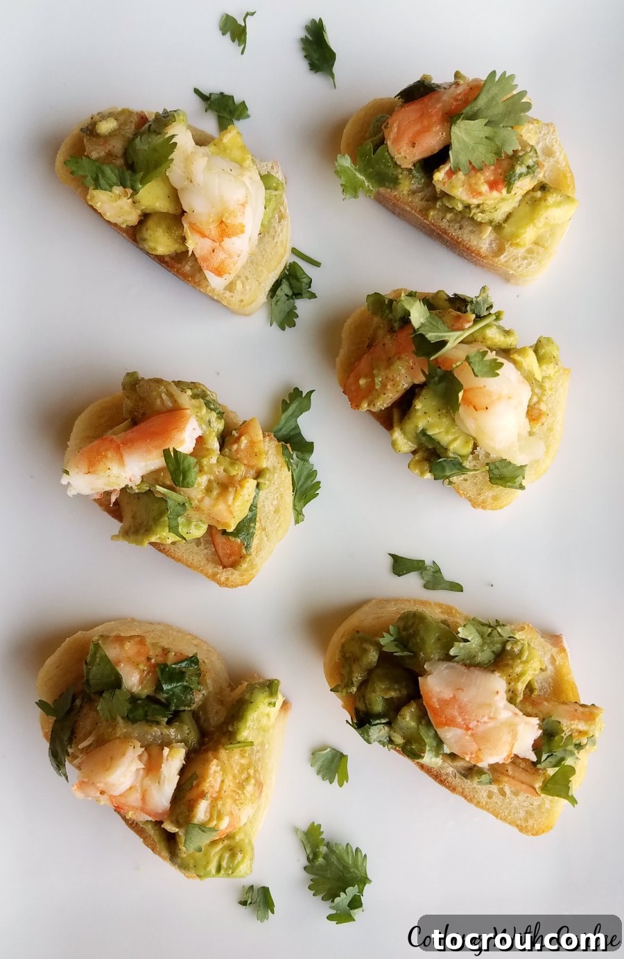 Delicious shrimp, creamy avocado, lime, cilantro and a hint of chili powder piled atop some delicious garlic bread. It is a one of a kind bruschetta appetizer that reminds me of our trip to the Houston shore. A beautifully arranged platter of shrimp and avocado toast appetizers, showcasing the vibrant colors and fresh ingredients, perfect for a gathering.