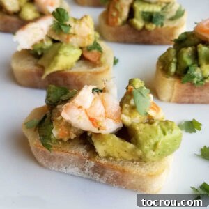 Avocado and shrimp mixture artfully piled on crispy baguette slices, garnished with fresh cilantro.
