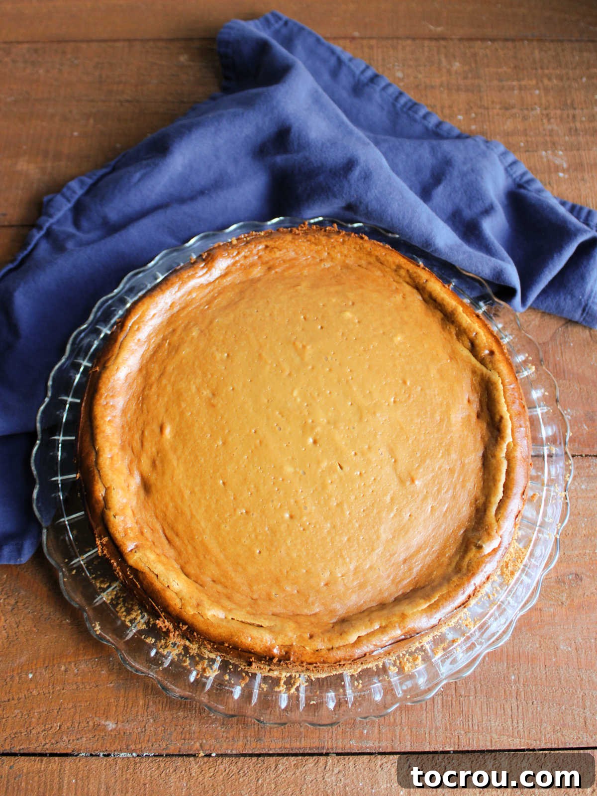Whole dulce de leche cheesecake on glass cake plate. 