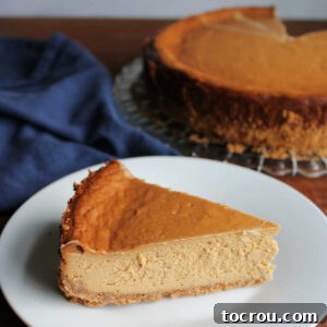 Slice of golden dulce de leche cheesecake on plate with remaining cheesecake in the background.