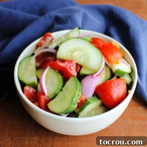 Small bowl piled high with marinated tomatoes, cucumbers, and red onion in homemade salad dressing.