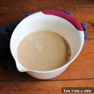 Mixing bowl filled with a smooth ice cream base made from sweetened condensed milk, coffee, and half and half, perfectly blended and ready for churning.